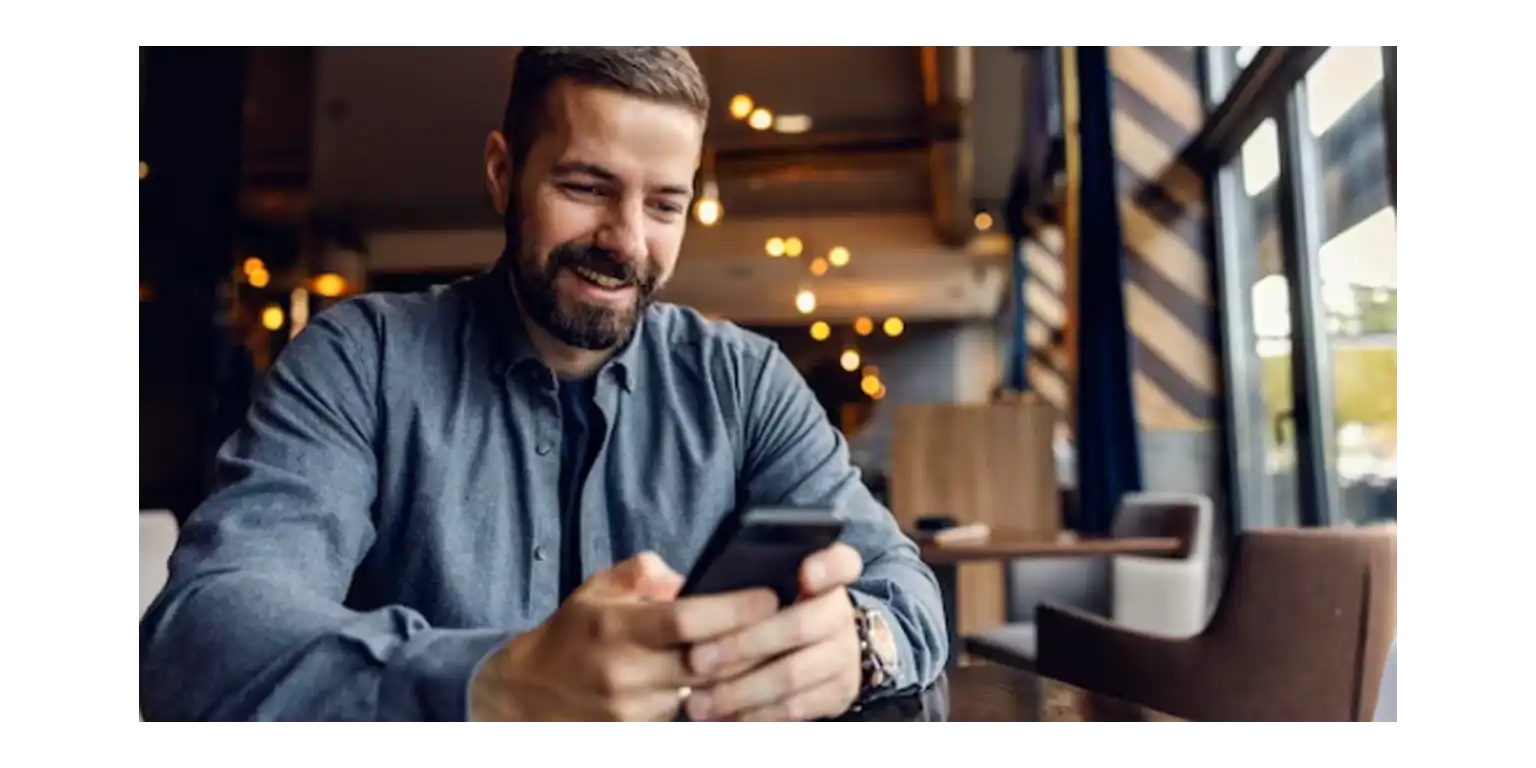 three female friends are sitting in a cafe, smiling and showing each other something on their phone screens