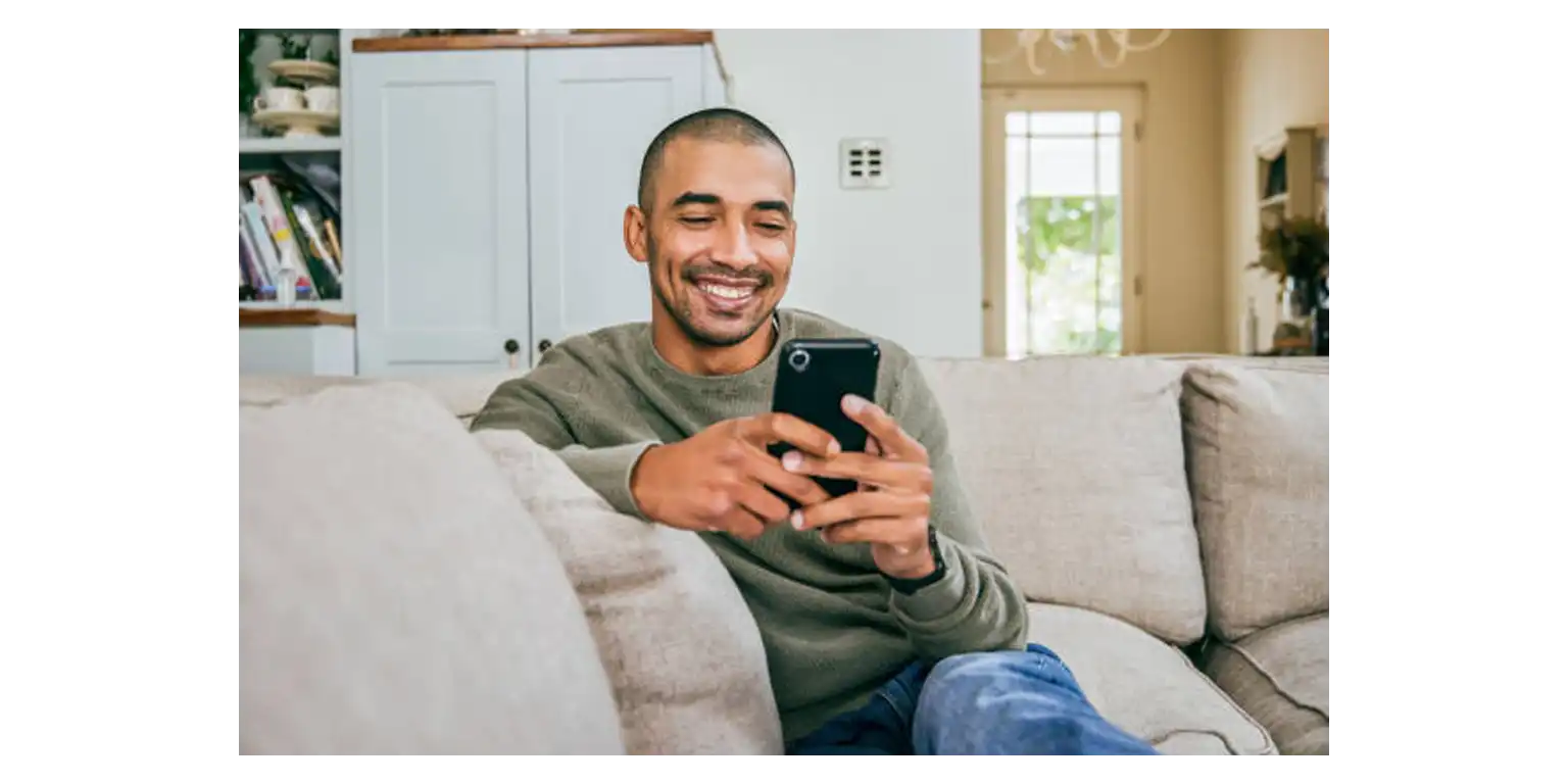 a smiling man uses his phone